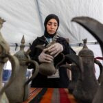 امرأة تحمل وعاء فخارياً قديماً، مع أواني أخرى.