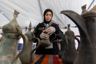 امرأة تحمل وعاء فخارياً قديماً، مع أواني أخرى.