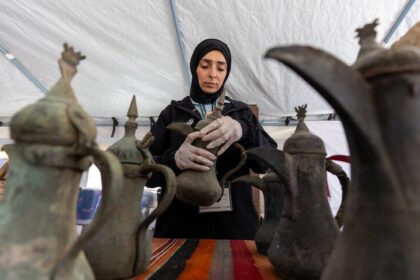 امرأة تحمل وعاء فخارياً قديماً، مع أواني أخرى.