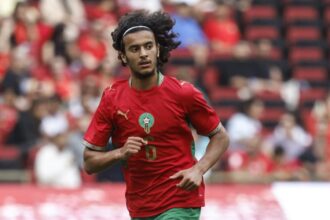 أيوب بوعدي، لاعب كرة القدم، رقم 6، يركض بقميص المنتخب المغربي.