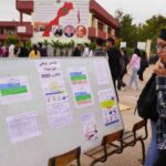 امرأة تقف أمام لوحة نتائج البكالوريا المعلقة.