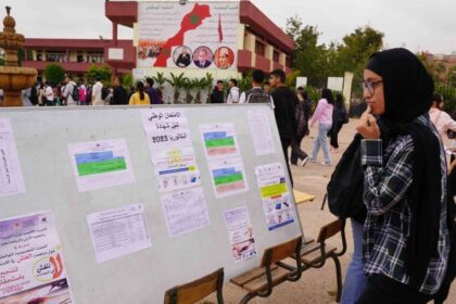 امرأة تقف أمام لوحة نتائج البكالوريا المعلقة.