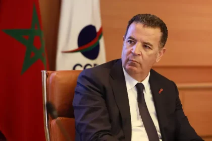 شكيب لعلج بجانب العلم المغربي