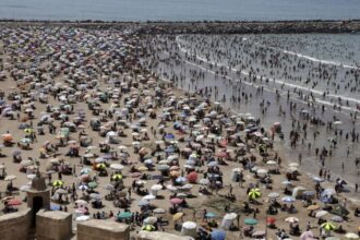 شاطئ مزدحم بالناس تحت أشعة الشمس الحارقة