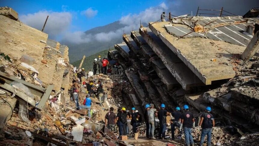 أشخاص يرتدون خوذات زرقاء يتفقدون آثار زلزال مدمر.
