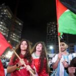 أشخاص يرتدون اللون الأحمر ويرفعون الأعلام في مدرجات كرة القدم.