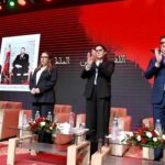 أشخاص يقفون أمام علم مغربي يحمل نجمة خضراء.