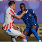 لاعب كرة قدم فرنسي يركض بالكرة في مباراة.