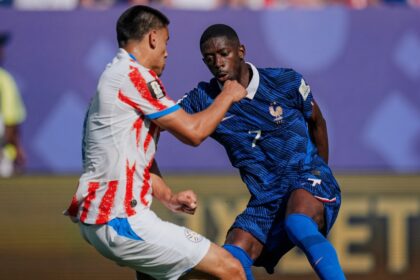 لاعب كرة قدم فرنسي يركض بالكرة في مباراة.