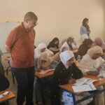 فتيات في قاعة امتحان يكتبن على الأوراق