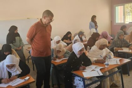فتيات في قاعة امتحان يكتبن على الأوراق