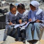 فتيات يرتدين الحجاب ويعملن بتركيز على مواد تعليمية.