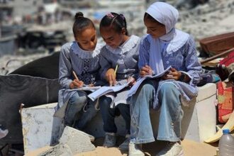 فتيات يرتدين الحجاب ويعملن بتركيز على مواد تعليمية.