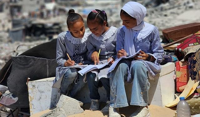فتيات يرتدين الحجاب ويعملن بتركيز على مواد تعليمية.