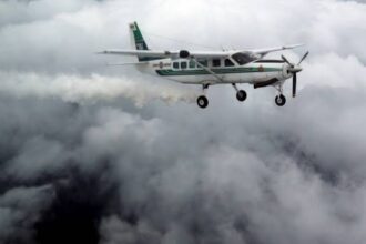 طائرة تلقيح سحب خضراء تحلق في سماء مليئة بالغيوم.
