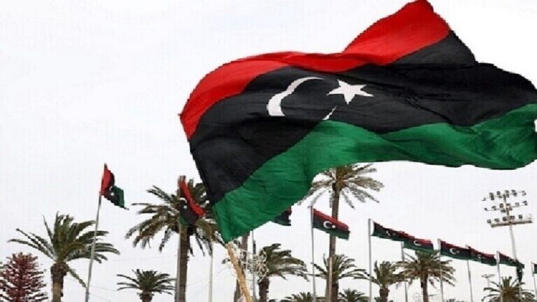 علم ليبي يرفرف في السماء، ألوانه حمراء وسوداء وخضراء.