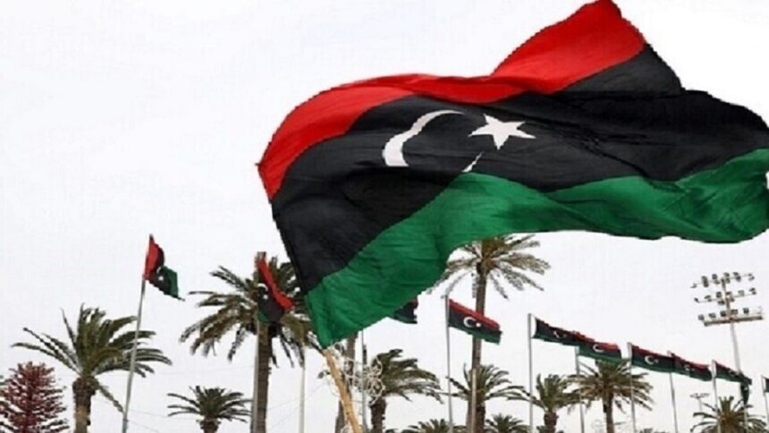 علم ليبي يرفرف في السماء، ألوانه حمراء وسوداء وخضراء.