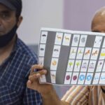 رجل يصور كتابًا مفتوحًا وبه بطاقة ذات أيقونات ملونة.