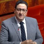 رجل يرتدي نظارة وربطة عنق يتحدث في مؤتمر.