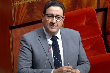 رجل يرتدي نظارة وربطة عنق يتحدث في مؤتمر.