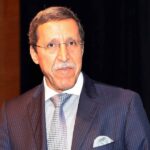 رجل يتحدث أمام خلفية باللون البني