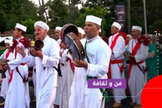 موسيقيون تقليديون يعزفون خلال موكب استعراضي بمراكش وسط حشود المتفرجين.