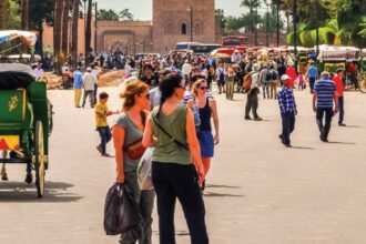 مشهد لساحة جامع الفنا بمراكش مع الخيول والعربات وسياح أجانب.