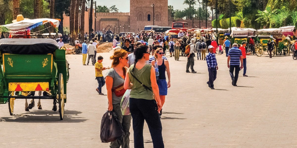 مشهد لساحة جامع الفنا بمراكش مع الخيول والعربات وسياح أجانب.