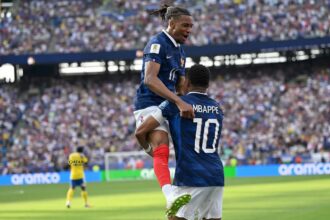 لاعب كرة قدم فرنسي يرتدي قميص مبابي يحتفل مع زميله.