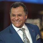 المهدي قطبي يرتدي بدلة داكنة وربطة عنق مبتسماً