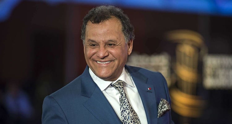 المهدي قطبي يرتدي بدلة داكنة وربطة عنق مبتسماً