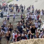 مهاجرون يركضون على شاطئ مليء بالإطارات المطاطية.