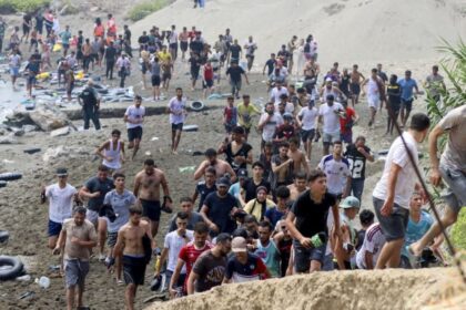 مهاجرون يركضون على شاطئ مليء بالإطارات المطاطية.