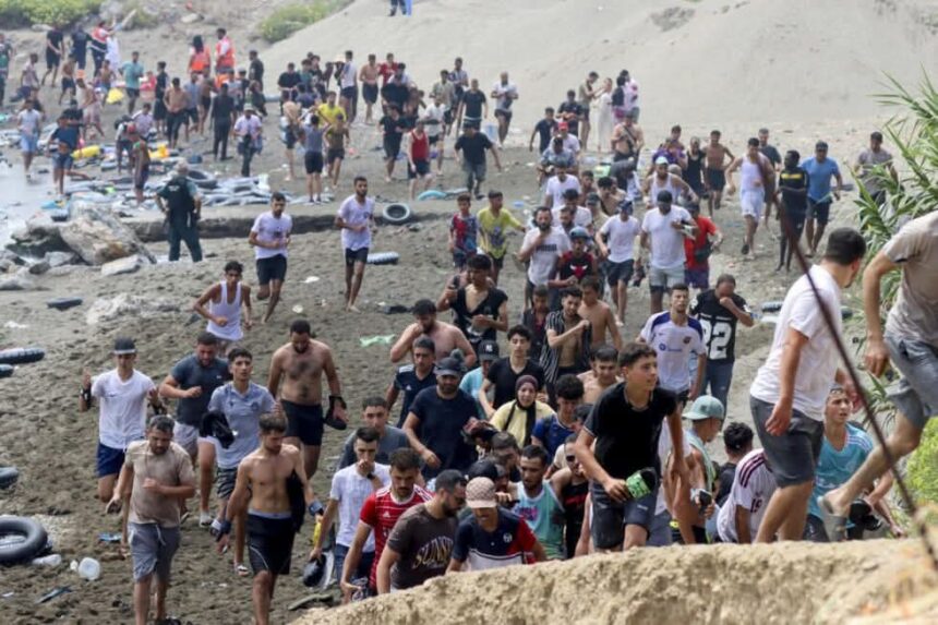مهاجرون يركضون على شاطئ مليء بالإطارات المطاطية.