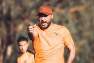 معين الشعباني يشير بيده في الزي البرتقالي