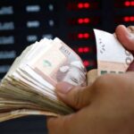 شخص يحمل نقودًا ورقية من عملات مختلفة