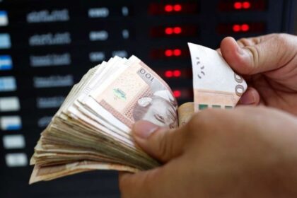 شخص يحمل نقودًا ورقية من عملات مختلفة