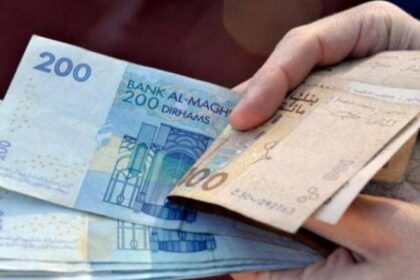 شخص يحمل ورقة نقدية من فئة 200 درهم.