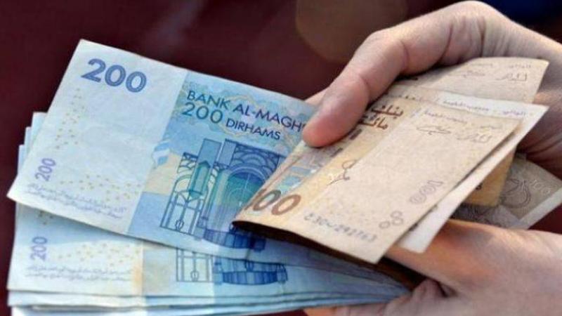 شخص يحمل ورقة نقدية من فئة 200 درهم.
