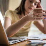 امرأة تحمل بطاقة ائتمان أمام حاسوب