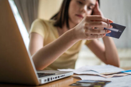 امرأة تحمل بطاقة ائتمان أمام حاسوب