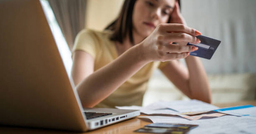 امرأة تحمل بطاقة ائتمان أمام حاسوب
