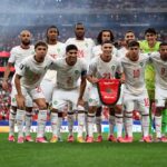 لاعب مغربي يحمل العلم الوطني في ملعب كرة قدم حاشد
