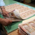 أوراق مالية وأيدٍ تحمل نقوداً.