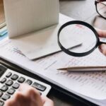 شخص ينظر إلى حاسبة، يراجع أرقامًا مالية