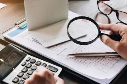 شخص ينظر إلى حاسبة، يراجع أرقامًا مالية
