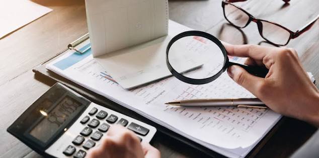 شخص ينظر إلى حاسبة، يراجع أرقامًا مالية