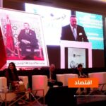 أشخاص يتحدثون على خشبة المسرح أمام شاشات عملاقة