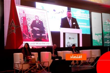 أشخاص يتحدثون على خشبة المسرح أمام شاشات عملاقة