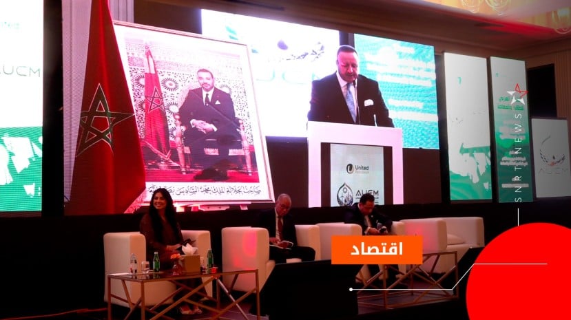 أشخاص يتحدثون على خشبة المسرح أمام شاشات عملاقة